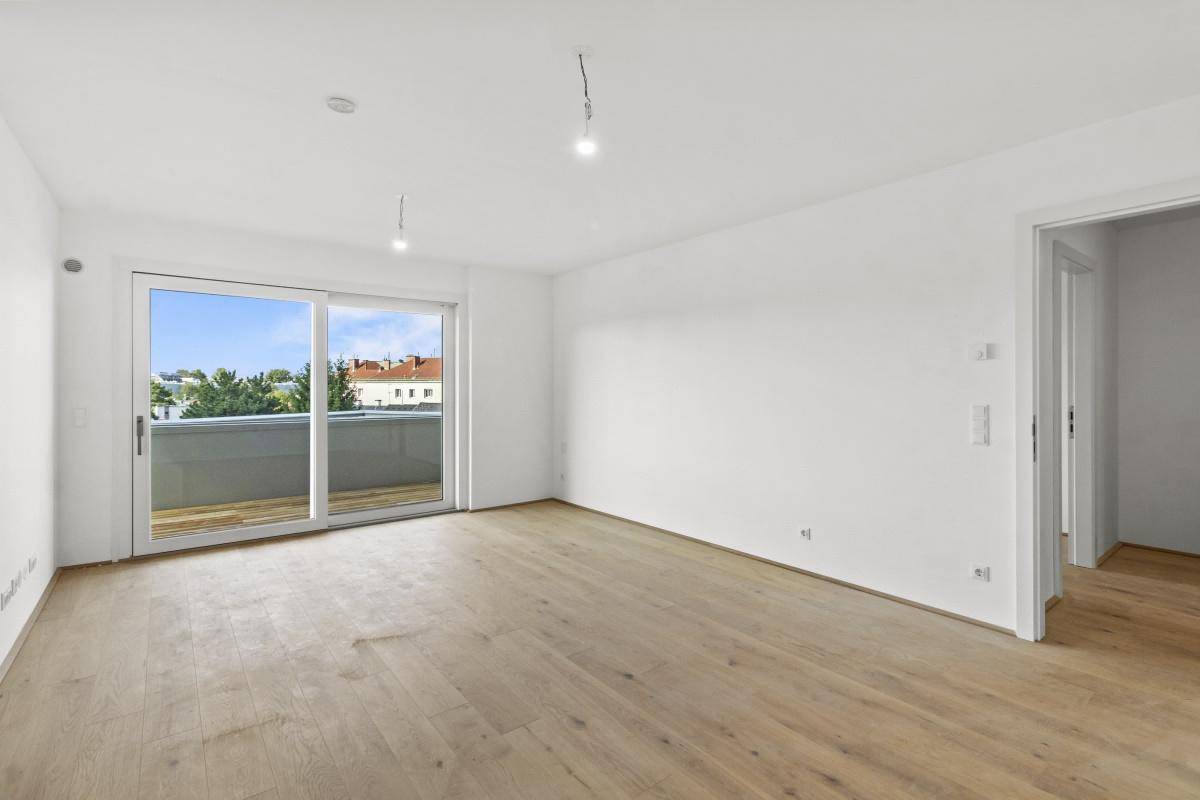 Geräumiger, heller Raum mit Holzboden und großem Fenster mit Balkonzugang.