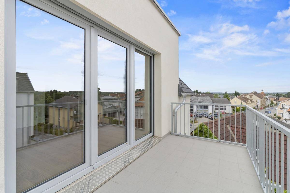 Balkon mit großen Fenstern und weitem Blick über die Dächer der Stadt und die Landschaft.