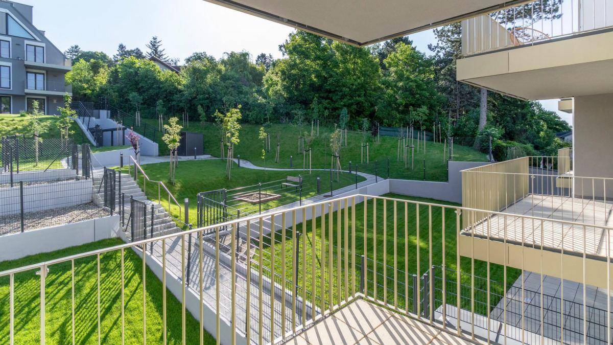 Blick vom Balkon auf die gepflegte Grünanlage mit Spielplatz und Wegen.