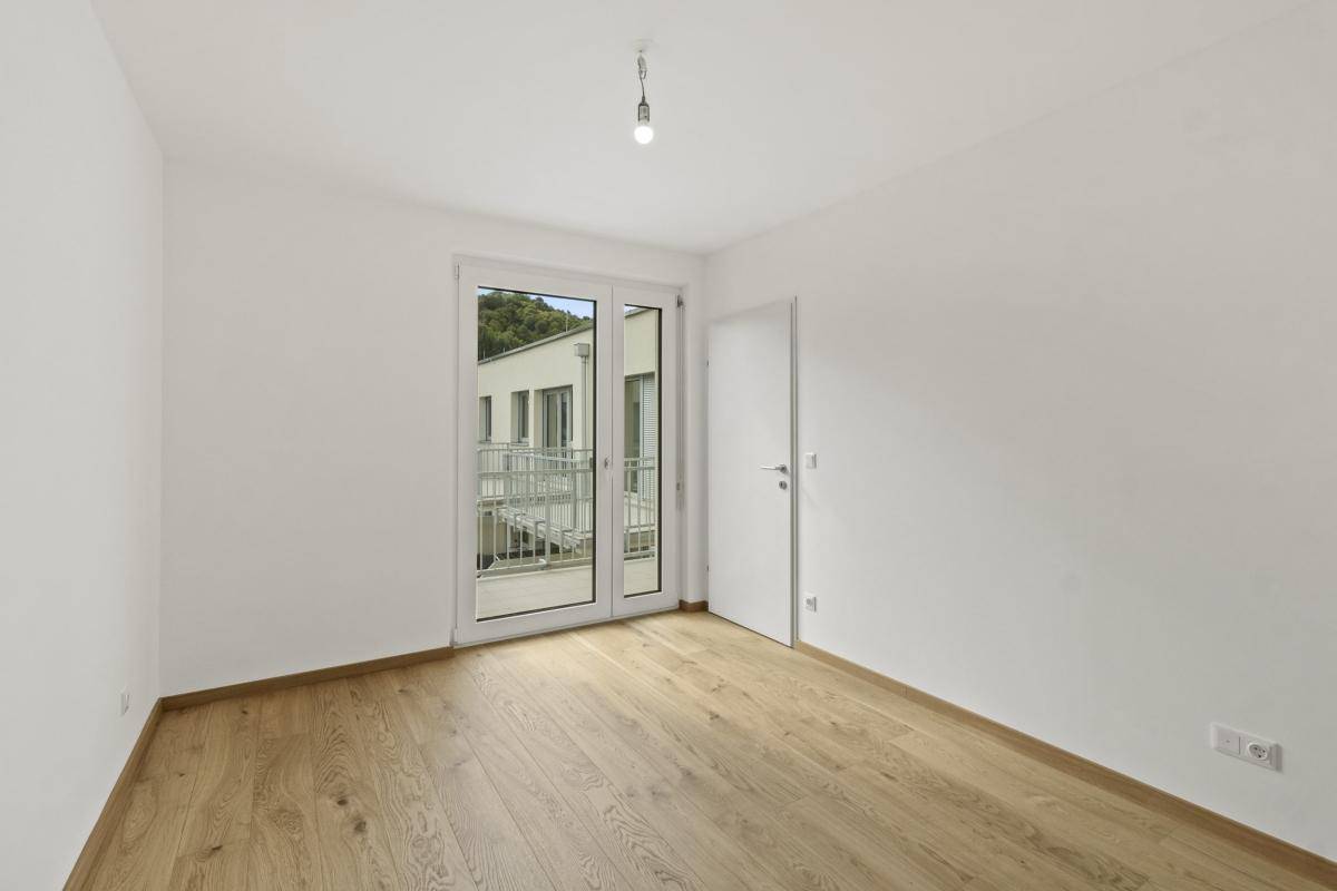 Helles Schlafzimmer mit Holzparkettboden und Zugang zu einem Balkon.
