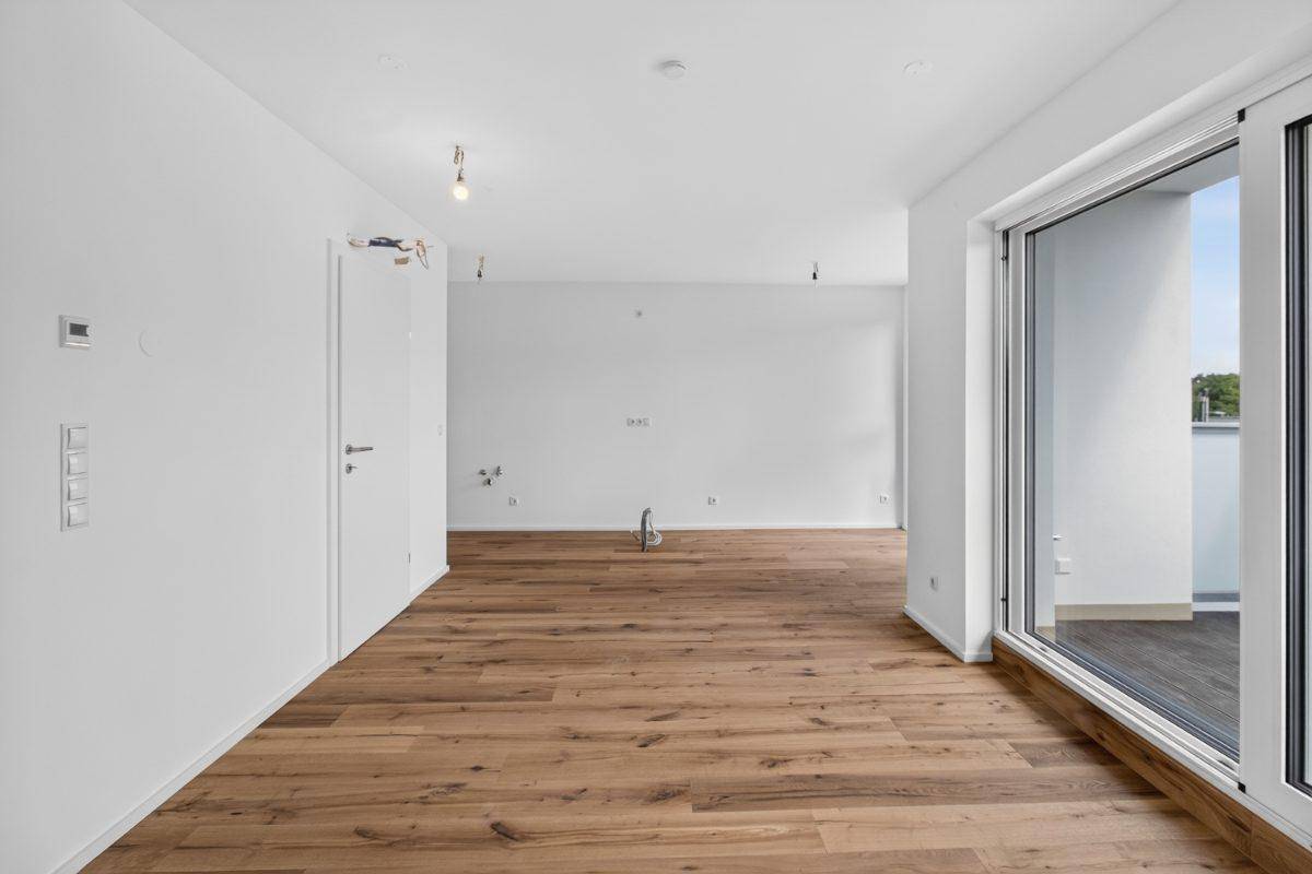 Lichtdurchfluteter Raum mit Holzboden und großem Fenster, ideal für Wohnzwecke.