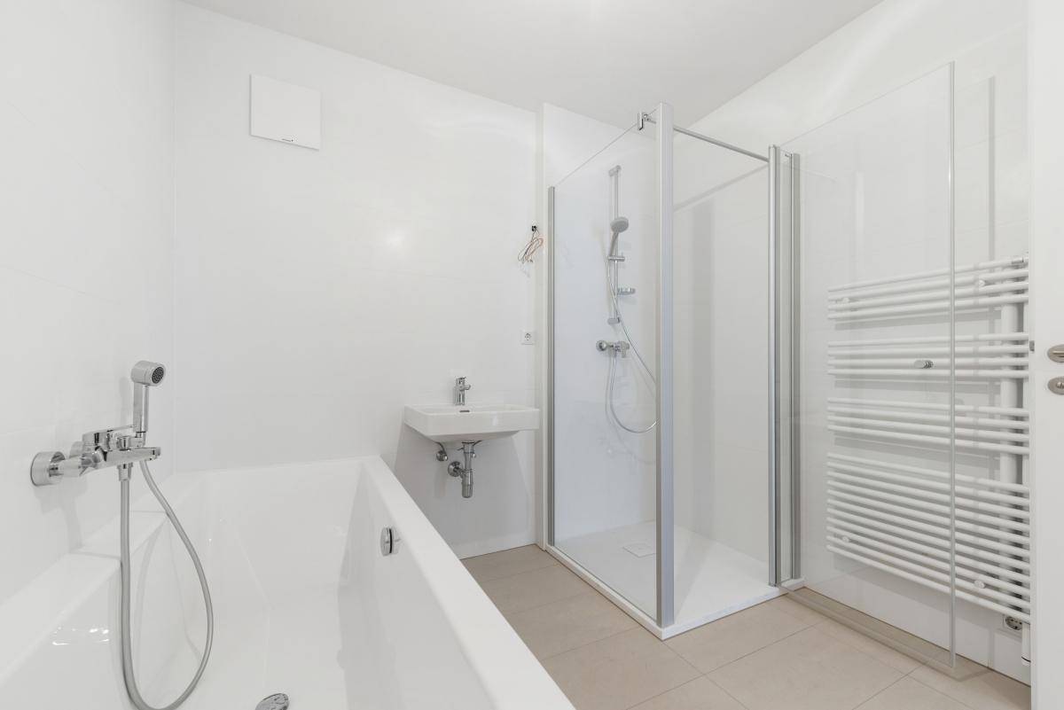 Modernes Badezimmer mit Badewanne, Duschkabine, Waschbecken und beheiztem Handtuchhalter.
