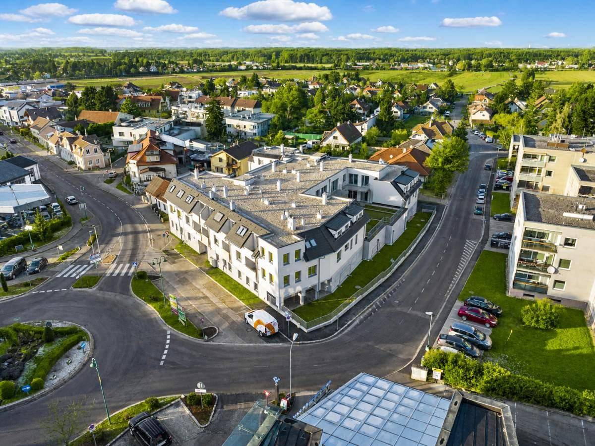 Luftaufnahme eines modernen Wohnkomplexes in einer ländlichen Umgebung mit viel Grün.