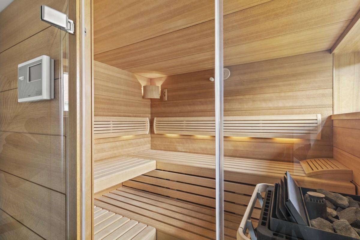Geräumige Holzsauna mit mehreren Bänken und einem modernen Saunaofen für Entspannung.