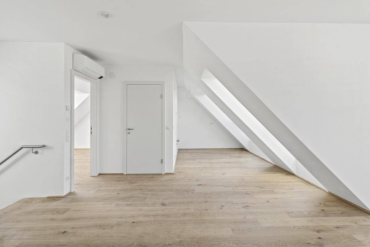 Heller Dachgeschossraum mit Holzboden, Dachschrägen und Klimaanlage.