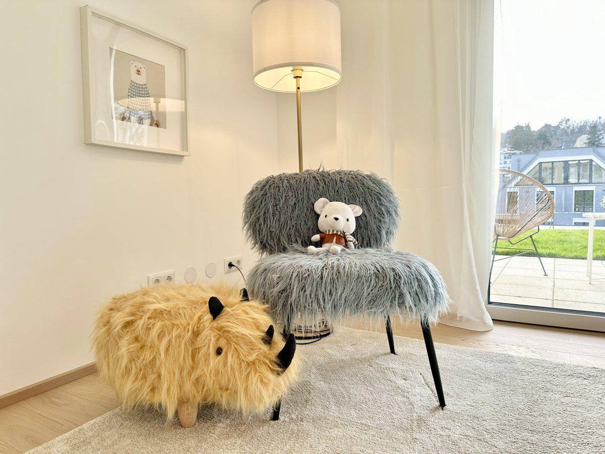 Detailansicht eines flauschigen Stuhls und eines Nashorn-Ottomanen in einem Kinderzimmer.