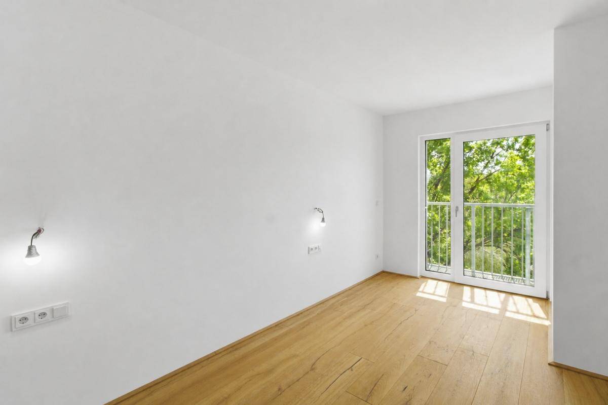 Heller Raum mit Holzfußboden und Zugang zu einem französischen Balkon, bietet viel Tageslicht.