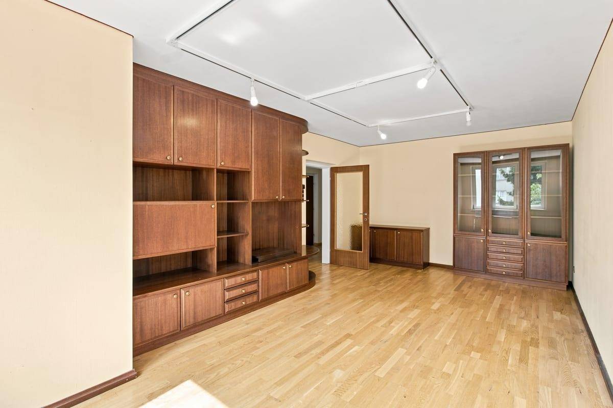 Großzügiges Wohnzimmer mit Holzboden und umfangreichen Einbauschränken für Stauraum.