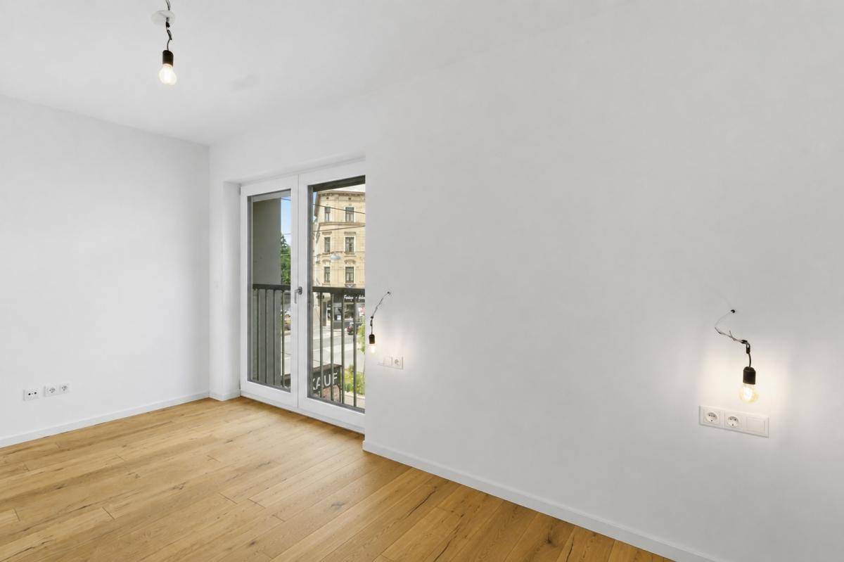 Helles Schlafzimmer mit Holzboden und französischem Balkon, ideal für natürliche Belüftung.