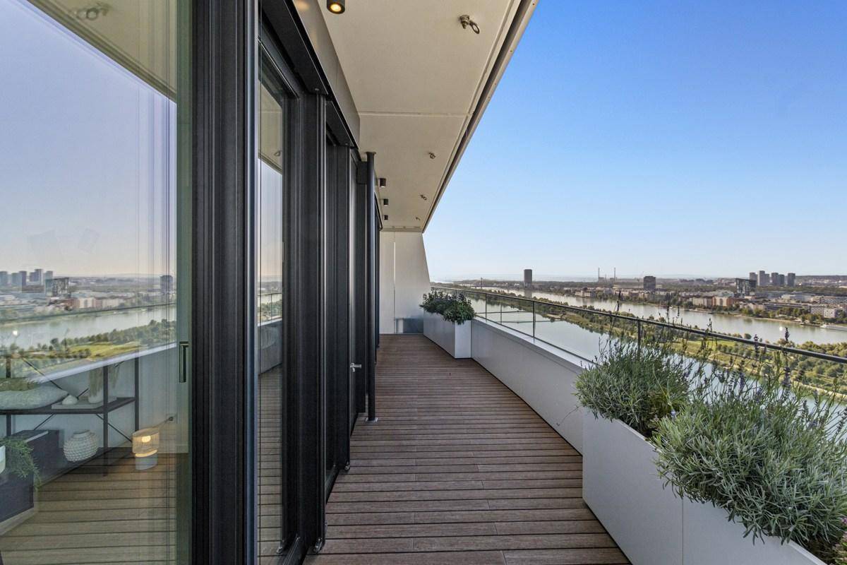 Weitläufige Terrasse mit Holzbelag und modernen Pflanzgefäßen, bietet einen beeindruckenden Stadtblick.