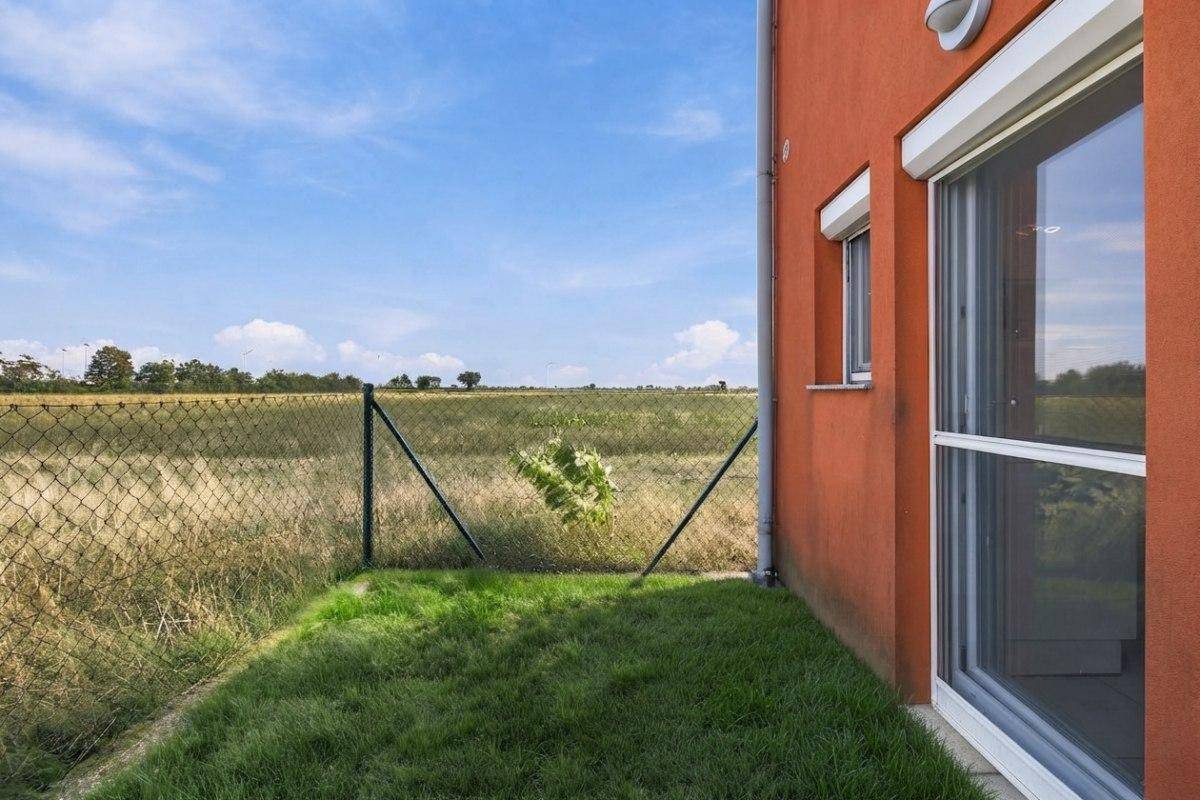 Kleiner Rasenbereich neben dem Haus mit Blick auf weite Felder und den Horizont.