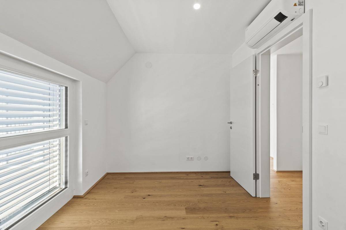Schlafzimmer mit Holzboden, Klimaanlage und Fenster mit Jalousien für Privatsphäre.