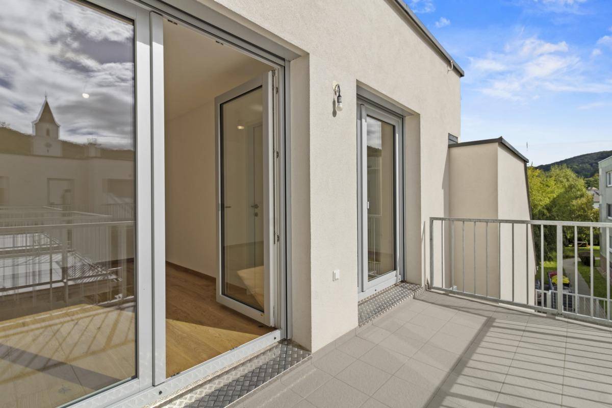 Balkon mit großen Glas-Schiebetüren, die Zugang zu einem hellen Innenraum ermöglichen.