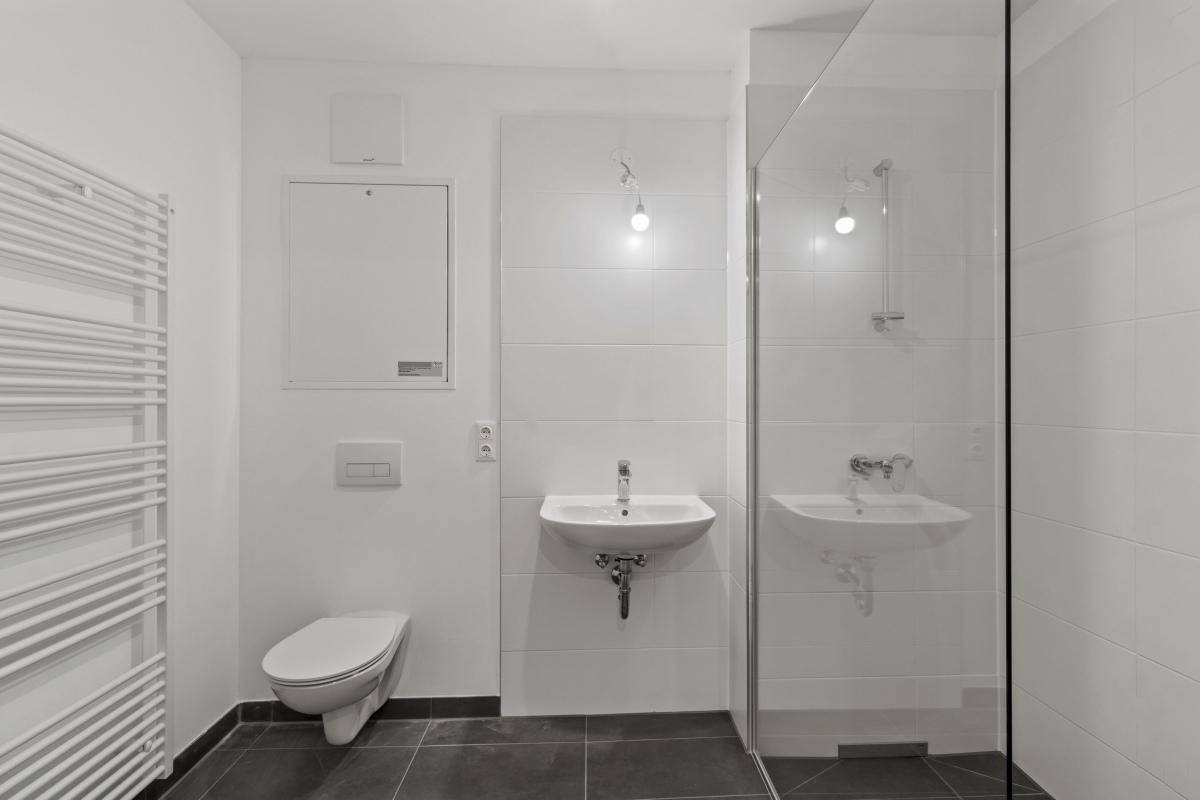 Kleines Badezimmer mit Dusche, WC und beheiztem Handtuchhalter, in modernem Design.