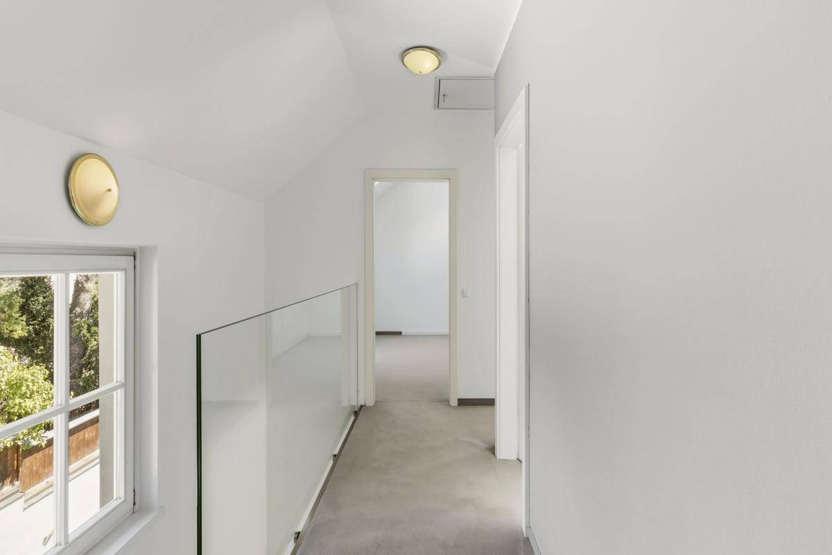 Heller Flur im Obergeschoss mit Glasgeländer und Blick nach draußen.