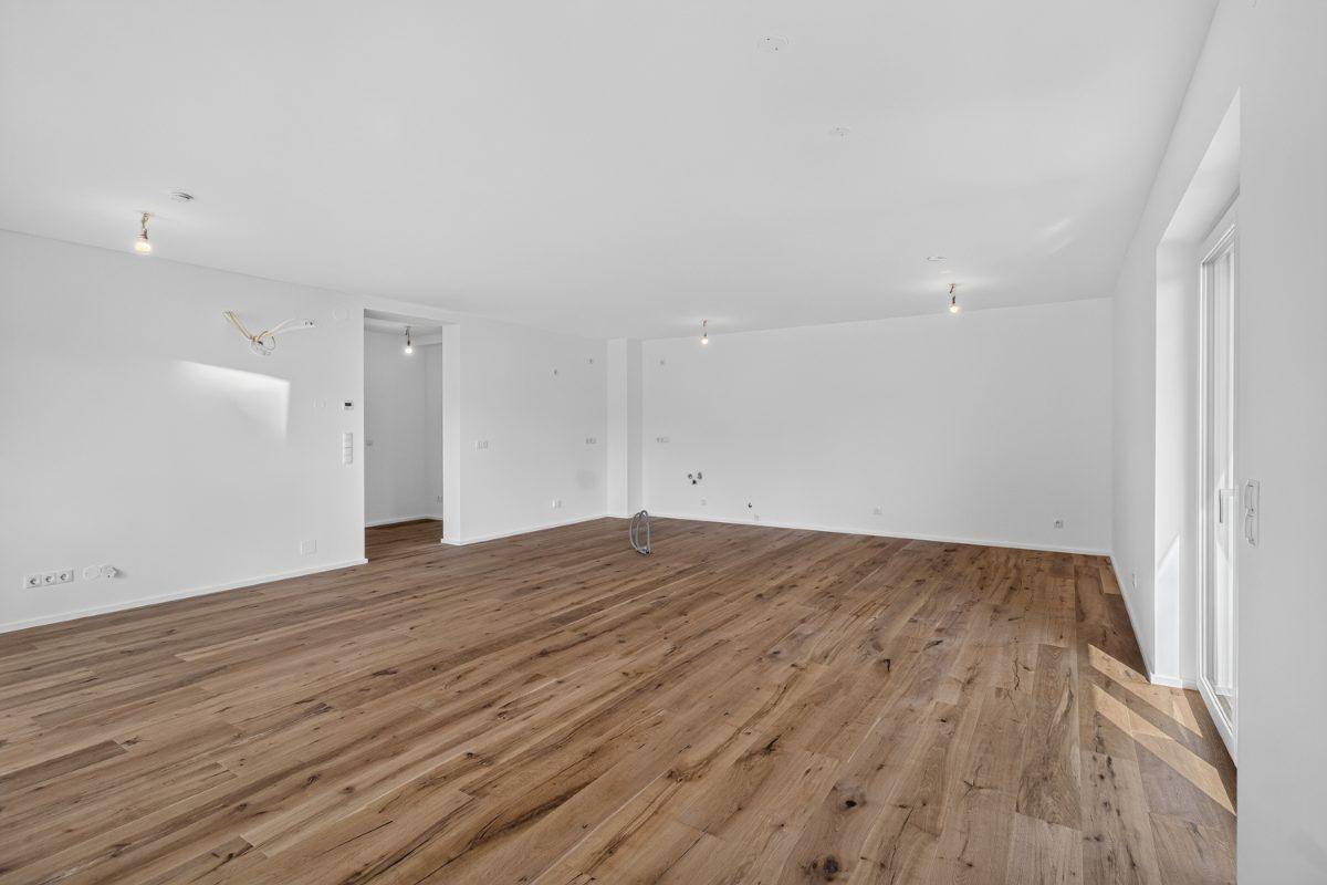 Geräumiger Wohnbereich mit Holzboden und hellen Wänden, bereit für individuelle Gestaltung.