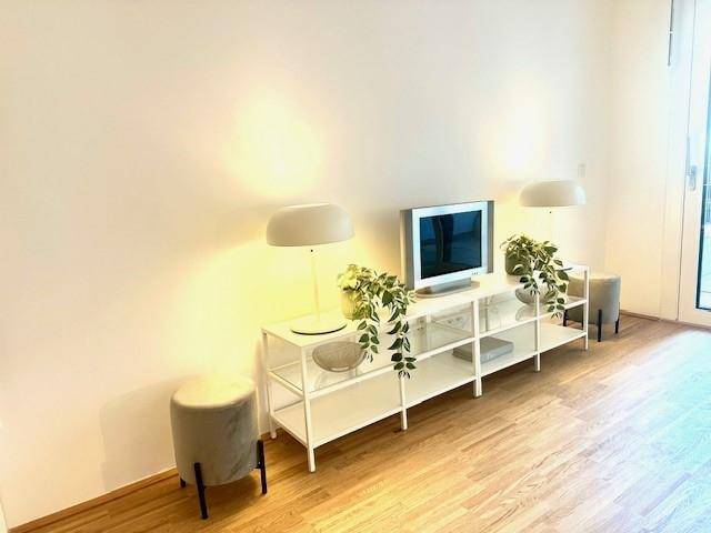 Heller Wohnraum mit Holzboden, weißer Wand und moderner TV-Bank mit Pflanzen.