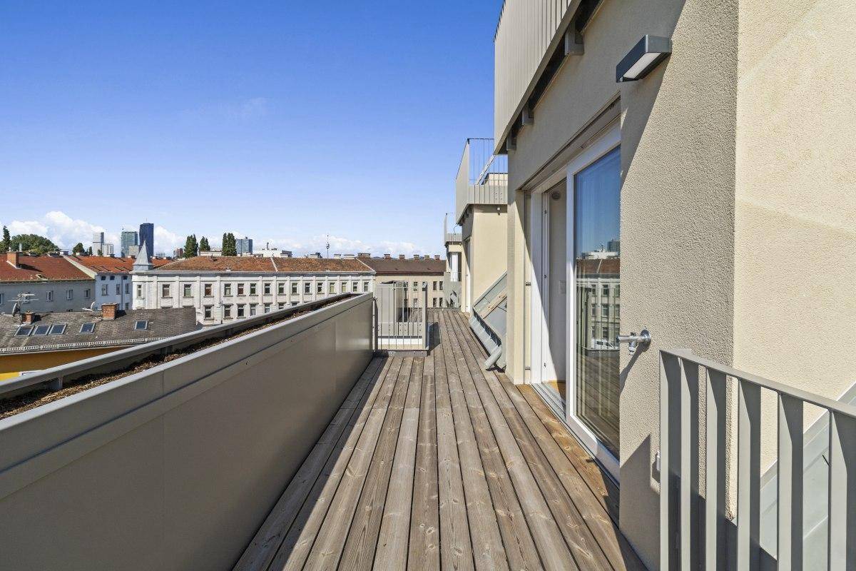 Langer Balkon mit Holzdielen und Metallgeländer, ideal für entspannte Stunden im Freien.
