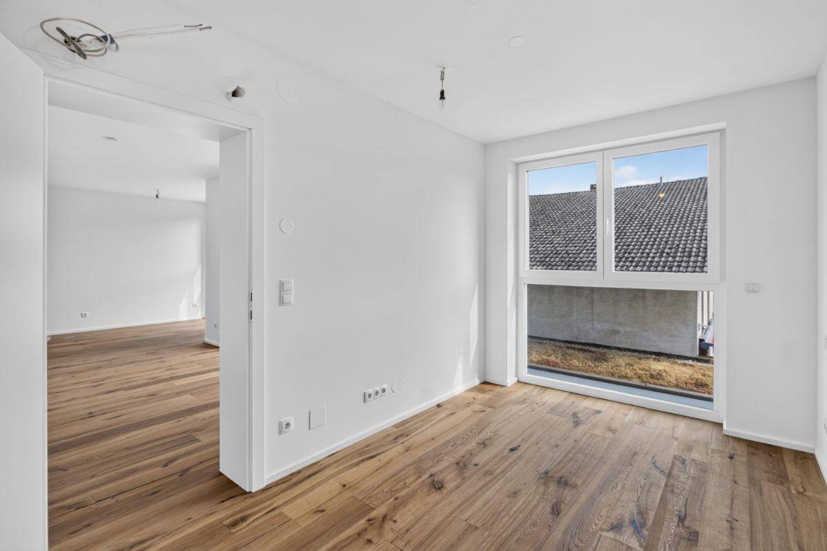 Weiteres helles Zimmer mit Holzboden und Fenster, ideal als Schlaf- oder Arbeitszimmer.