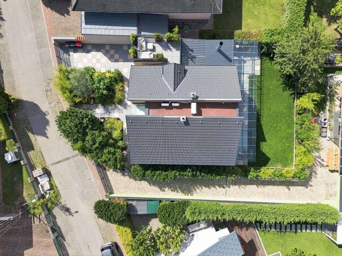 Vogelperspektive eines Wohnhauses mit Flachdach, Garten und angrenzender Terrasse.
