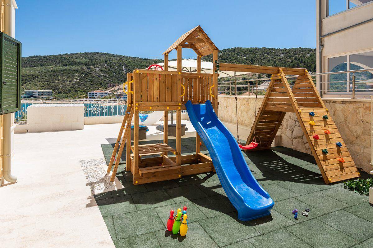 Kinderspielplatz mit Rutsche und Klettergerüst auf weichem Untergrund im Freien.