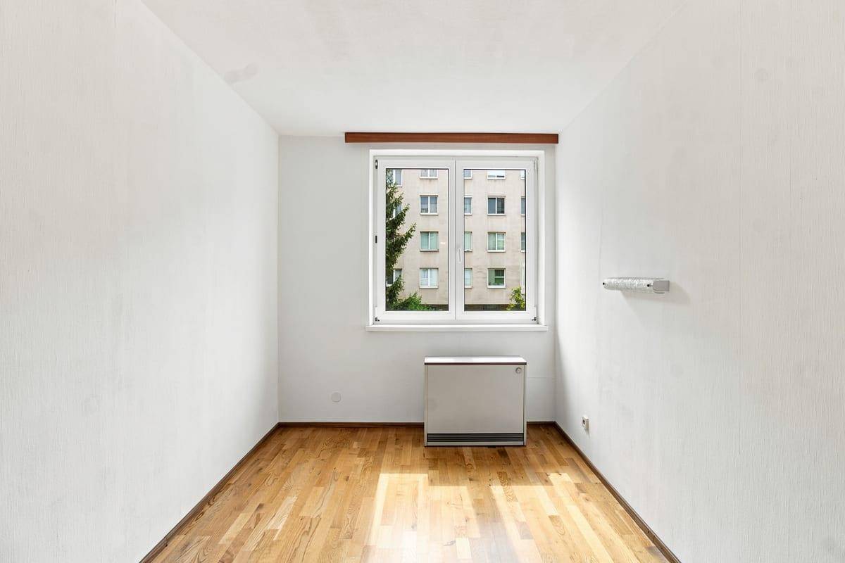 Ruhiges Schlafzimmer mit Holzboden und Fenster, ideal für erholsame Nächte.
