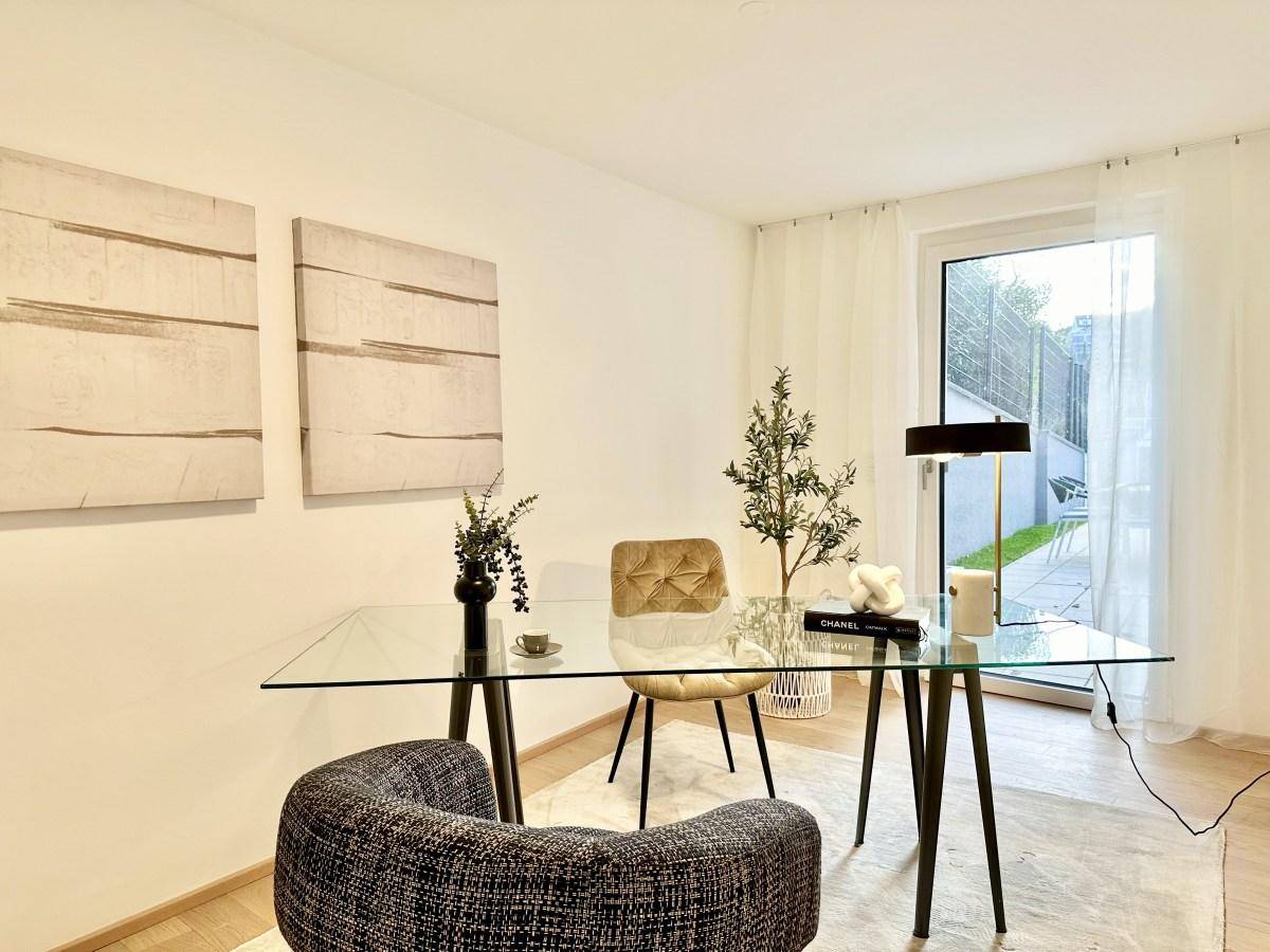 Modernes Arbeitszimmer mit Glastisch, bequemen Stühlen und Zugang zu einem Außenbereich.