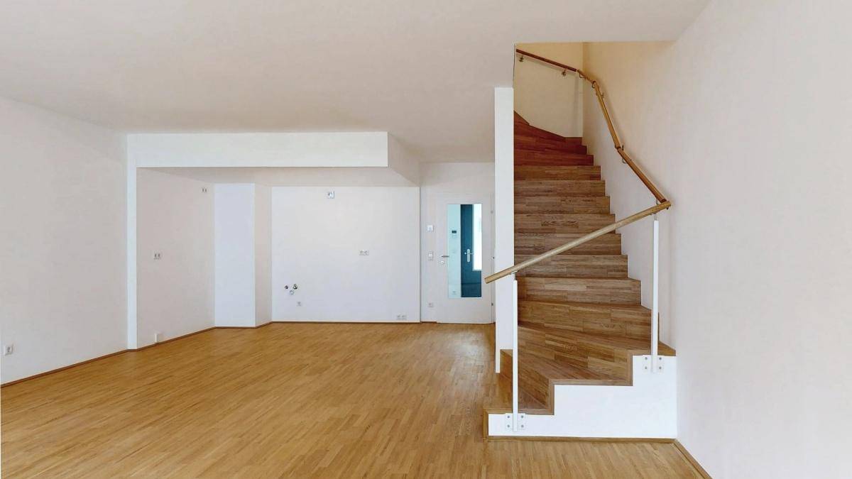 Geräumiger Wohnbereich mit eleganter Holztreppe und hellem Parkettboden.