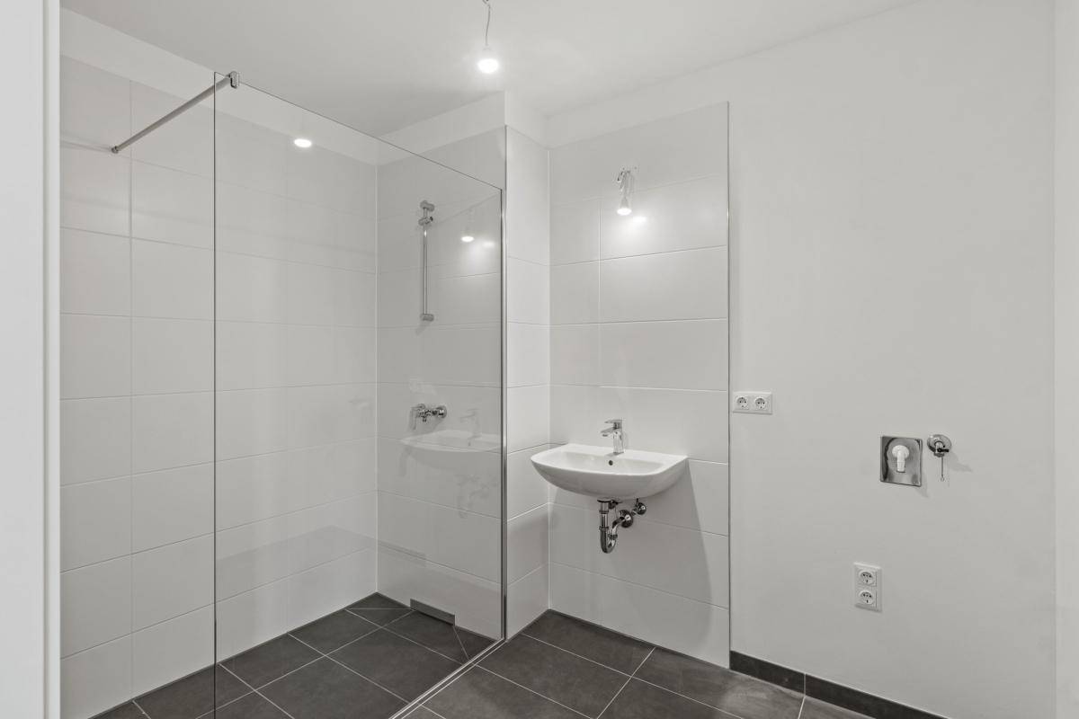 Modernes Badezimmer mit ebenerdiger Dusche, Waschbecken und Fliesenboden.