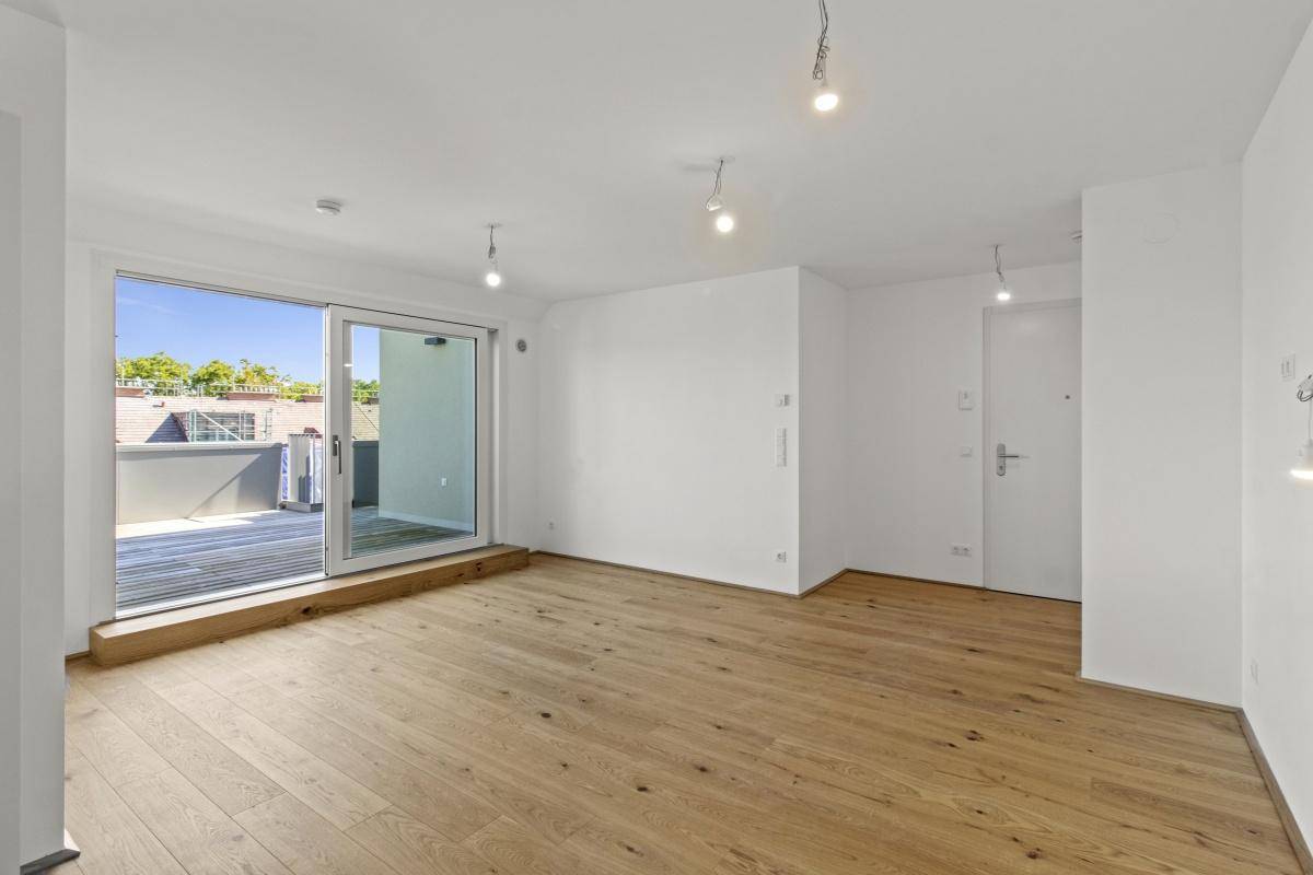 Heller Wohnraum mit Eichenparkettboden und Zugang zu einer großzügigen Terrasse.