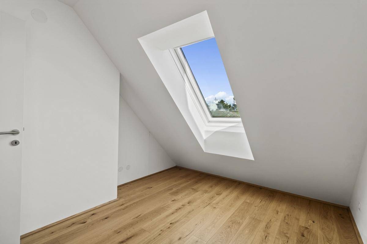Lichtdurchfluteter Raum mit Holzboden und einem großen Dachfenster, das viel Helligkeit spendet.