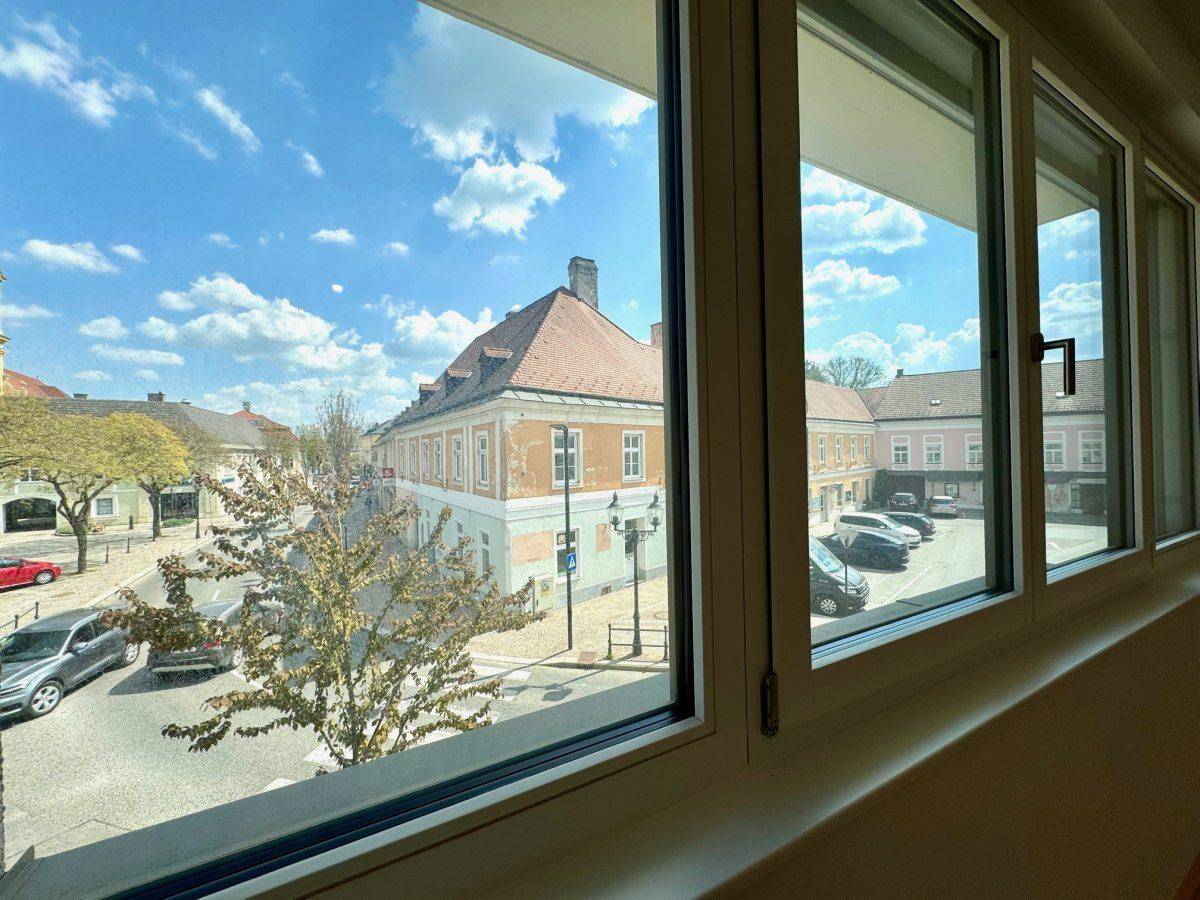 Ausblick aus dem Fenster auf die belebte Straße und die umliegenden Gebäude der Stadt.