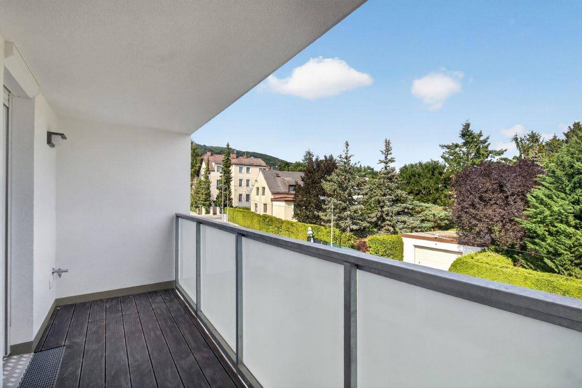 Heller Balkon mit Holzdielen und weitem Blick über die Wohngegend und grüne Umgebung.