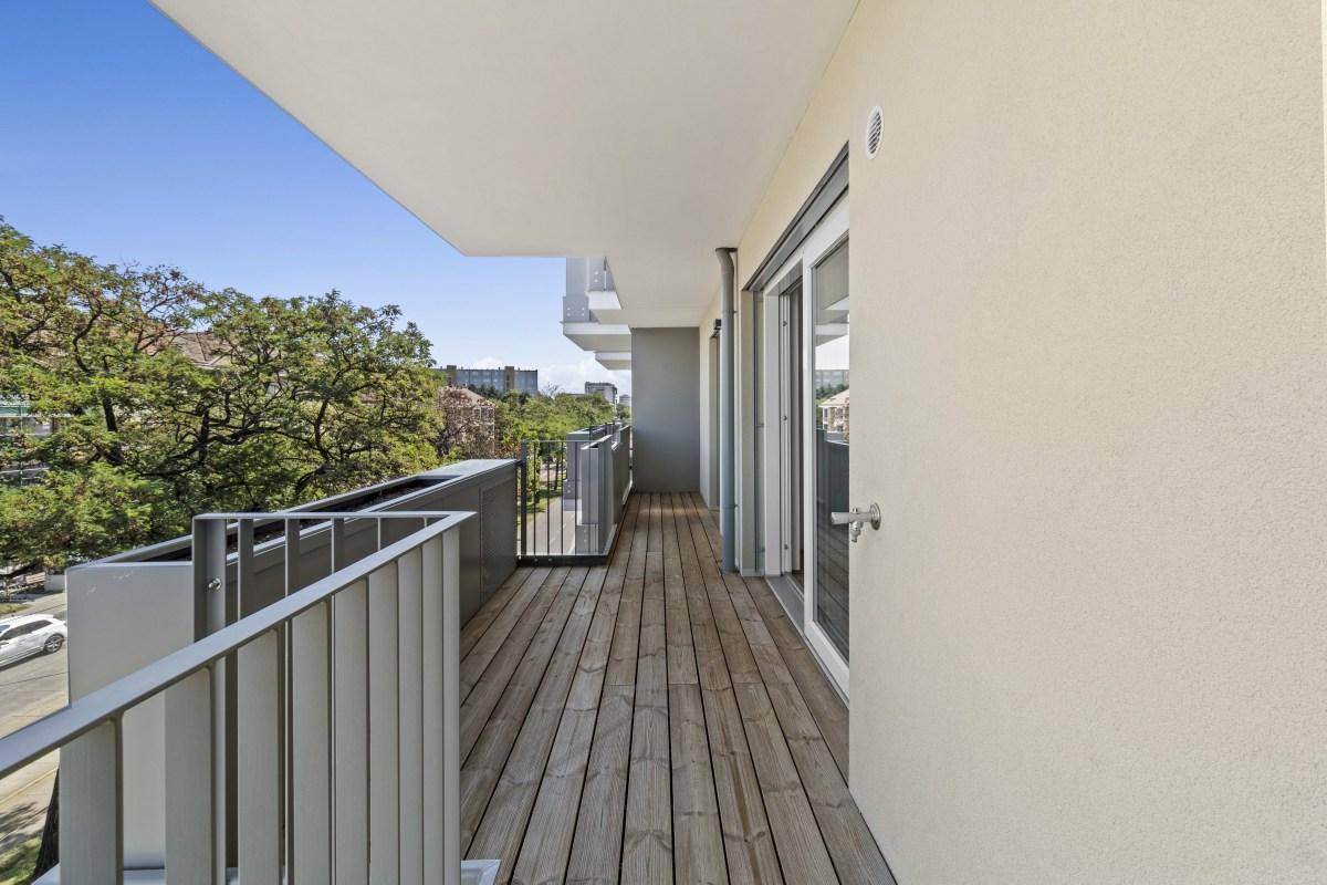 Langer Balkon mit Holzboden und Blick auf die Umgebung, bereit für individuelle Gestaltung.