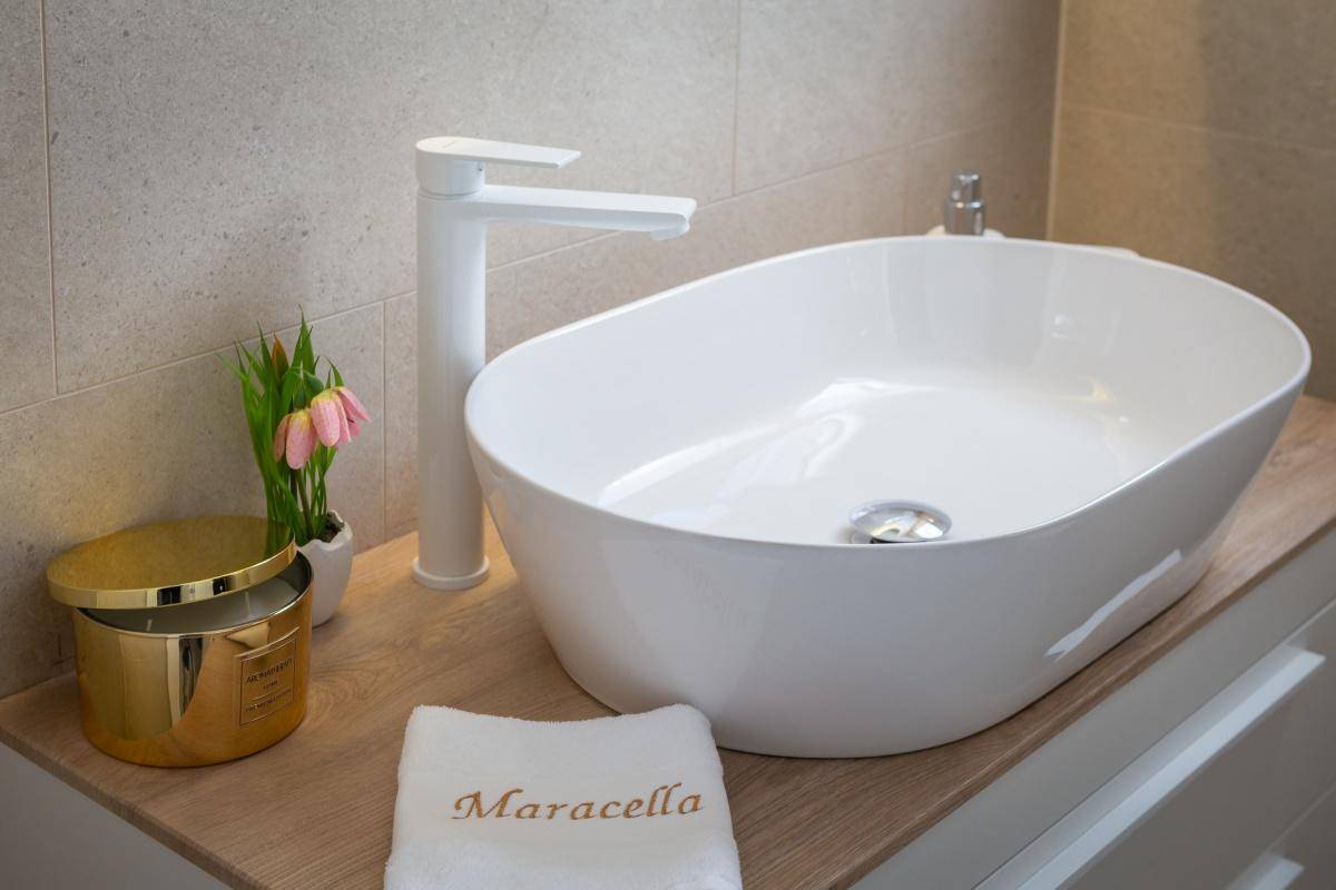 Detailansicht des modernen Waschbeckens mit weißer Armatur und dekorativen Elementen im Badezimmer.