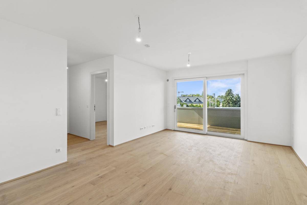 Heller Wohnbereich mit Holzboden und großer Schiebetür zum Balkon.