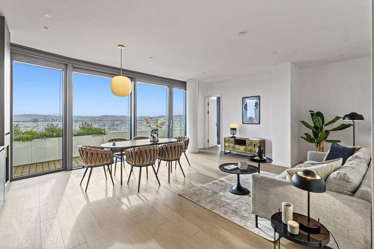Heller Wohn- und Essbereich mit eleganten Möbeln und raumhohen Fenstern zum Balkon.