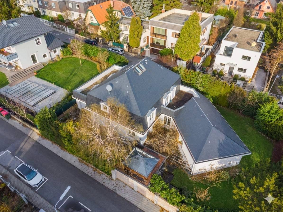 Luftaufnahme des Anwesens mit großem Garten, mehreren Terrassen und umliegenden Wohnhäusern in der Nachbarschaft.