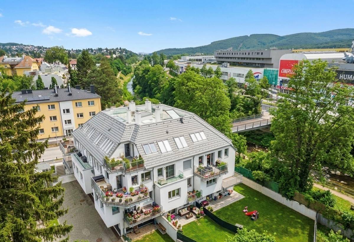 Luftaufnahme eines modernen Wohngebäudes mit Balkonen und grüner Umgebung, eingebettet in die Landschaft.