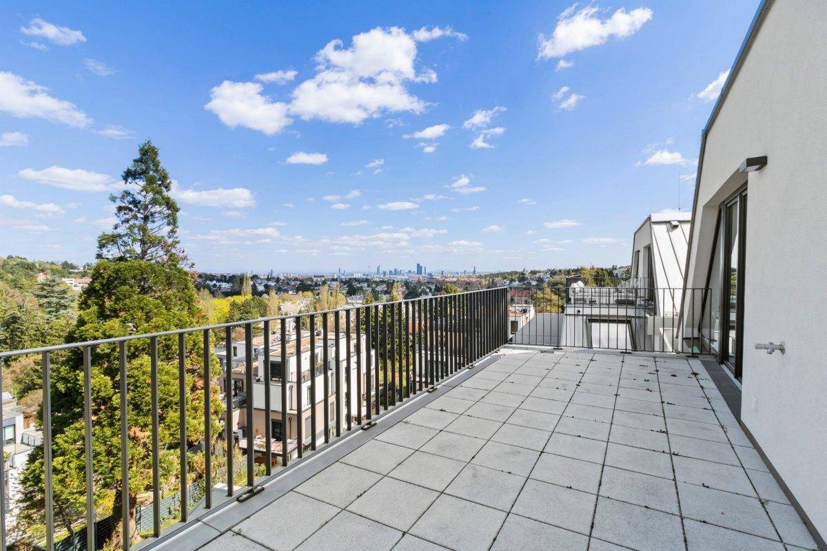 Große Terrasse mit Fliesenboden und weitem Blick über grüne Hügel und die Stadt.
