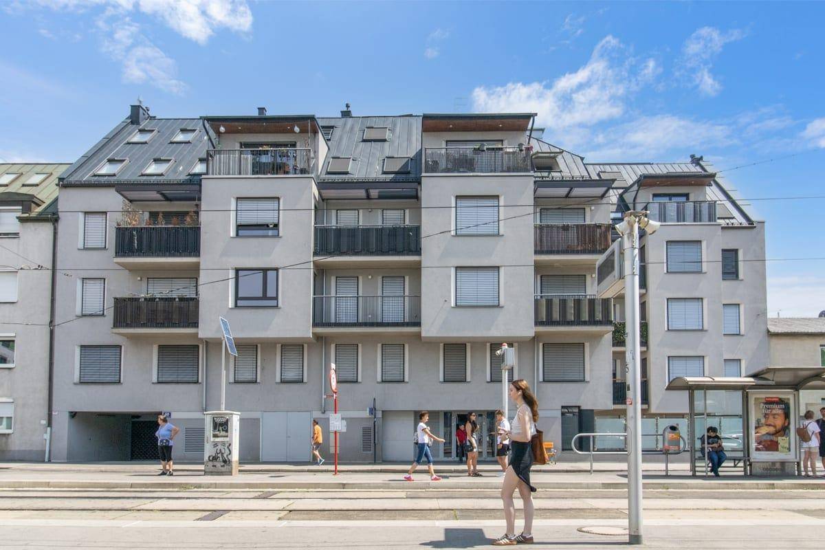 Moderne Wohnanlage mit Balkonen und großen Fenstern an einer städtischen Straße.