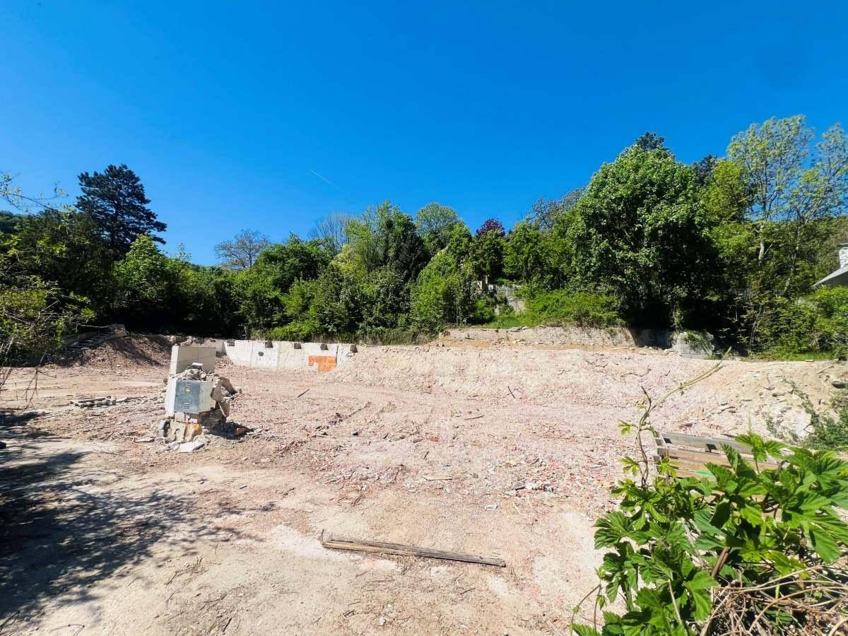 Weitläufiges Baugrundstück mit Erdaushub und vorbereiteter Fläche für Neubauten, umgeben von Natur.