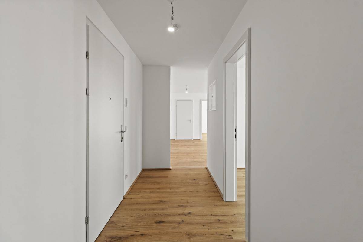 Heller Flur mit Eichenparkettboden und weißen Wänden in einem modernen Apartment.