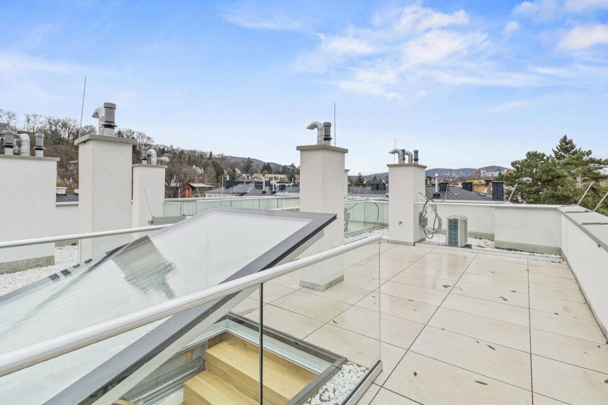 Weitläufige Dachterrasse mit Fliesenboden und Panoramablick auf die umliegende Hügellandschaft.