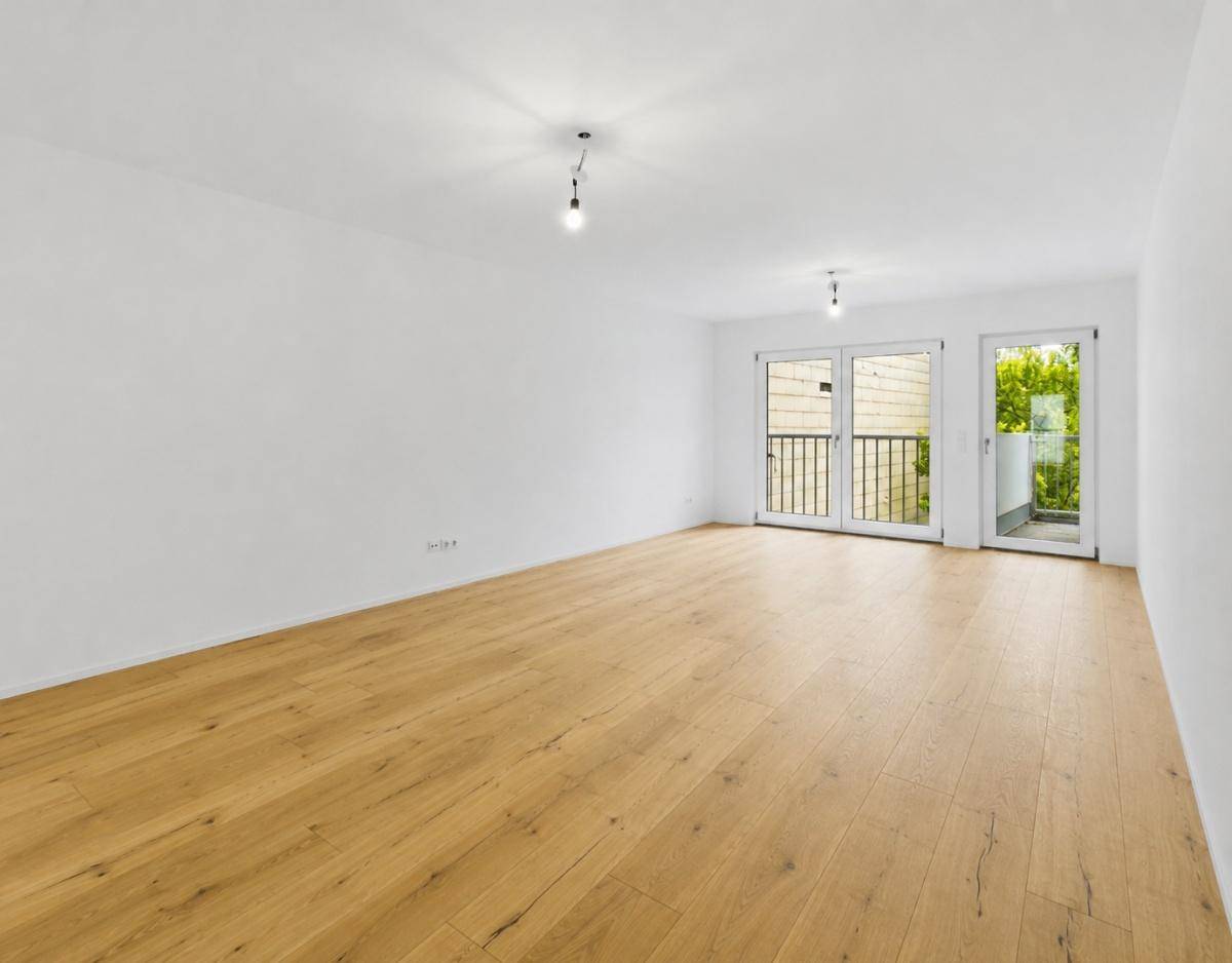 Geräumiger, heller Raum mit Holzparkett und zwei französischen Balkonen.