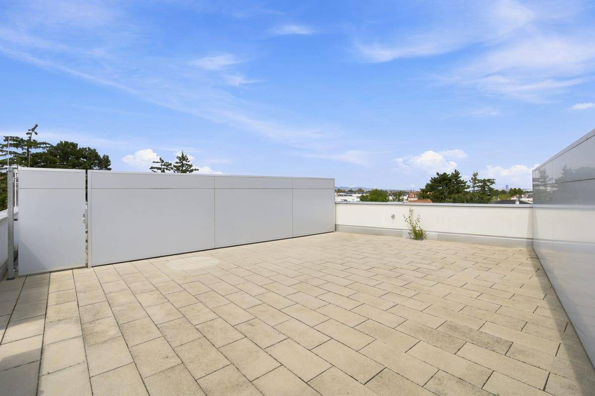 Geräumige Dachterrasse mit Steinplatten und weitem Blick über die Umgebung.