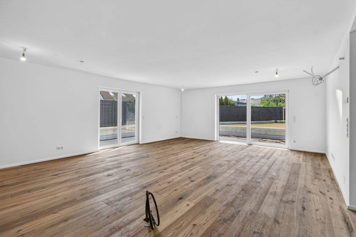 Geräumiges Wohnzimmer mit Holzboden und großen Schiebetüren zum Garten.