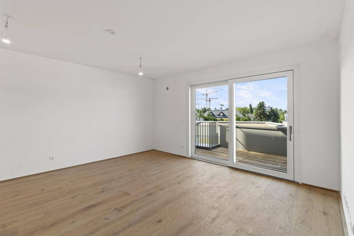 Lichtdurchfluteter Wohnraum mit Holzboden und Schiebetür zum Balkon mit Stadtblick.