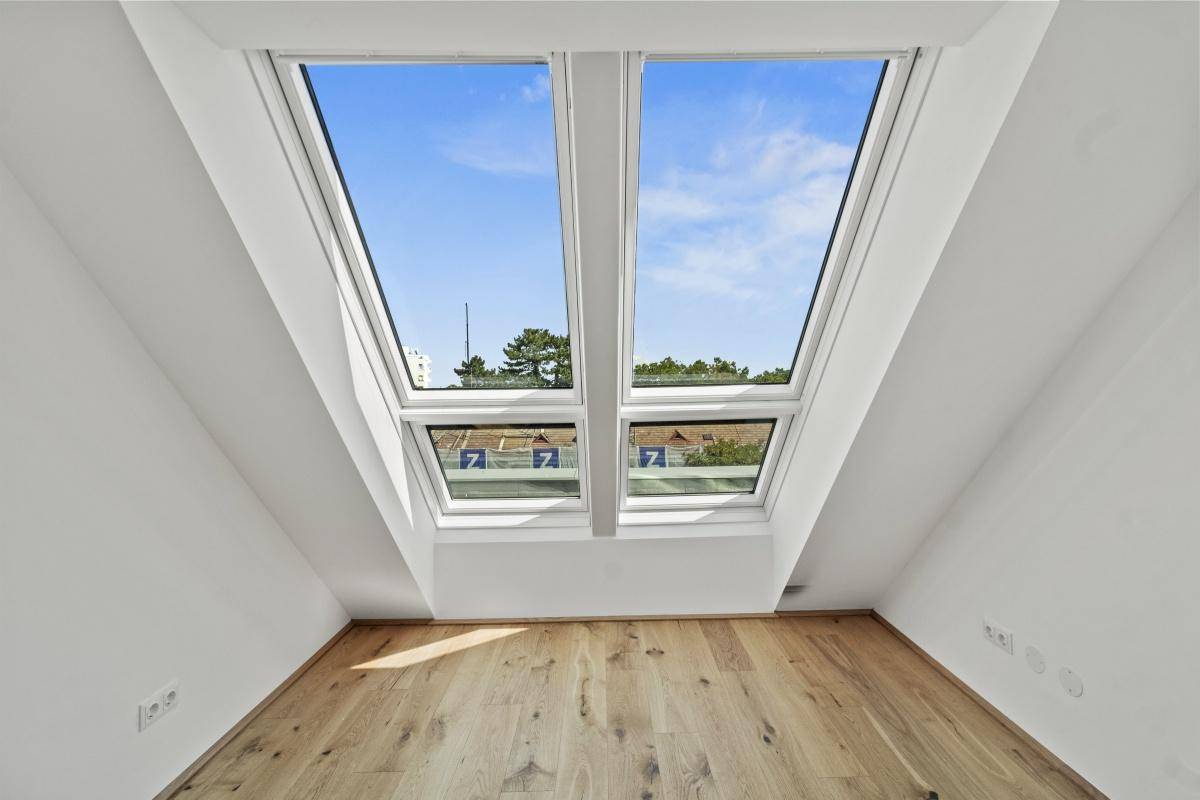 Heller Raum im Dachgeschoss mit zwei großen Dachfenstern und Holzboden.