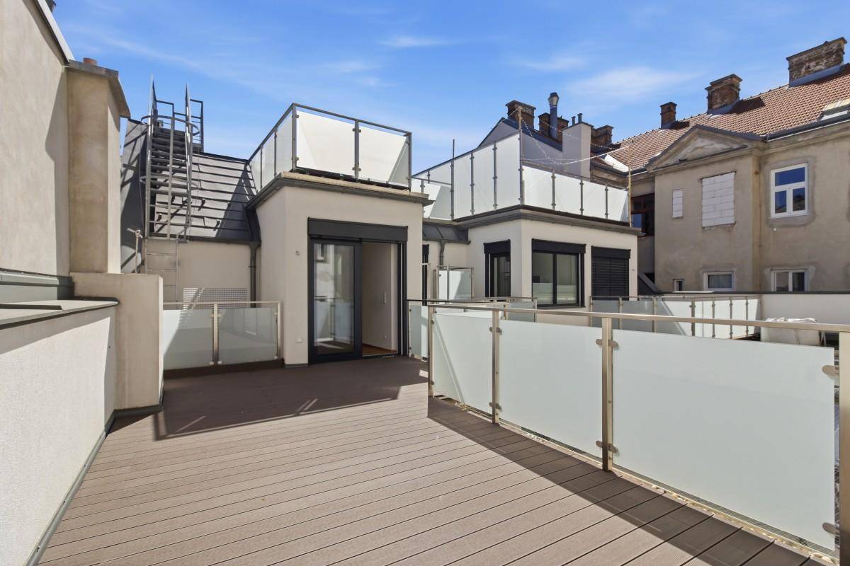 Weitläufige Dachterrasse mit Holzbelag und Zugang zu weiteren Dachflächen.
